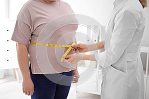 Doctor measuring waist of overweight woman in clinic