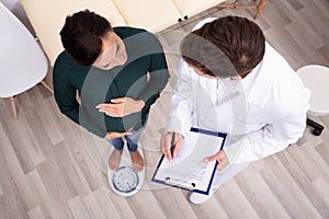 Doctor Measuring Weight Of Pregnant Woman