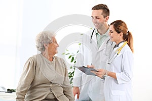 Doctor and medical assistant working with elderly patient photo