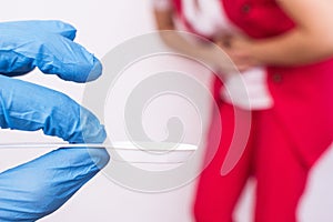 Doctor in a medical glove holding a spoon with medicine in the background a girl holding her stomach, stomach pain, gastritis