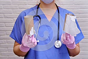 A doctor in medical gloves is holding a run-out toilet paper. Problems with toilet paper in the coronavirus epidemic, the concept