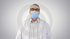 Doctor in medical mask against Coronavirus Covid-19 breathing heavily on gradient background.