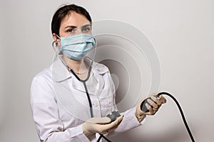 Doctor in a medical mask, cardiologist measures blood pressure with a blood pressure monitor.