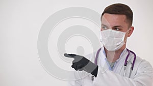 A doctor in a medical mask makes remarks, pointing a finger to the side.