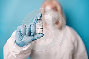 Doctor in medical PPE suit with Coronavirus vaccine vial. Doctor preparing a dose for a patient of the third vaccine for