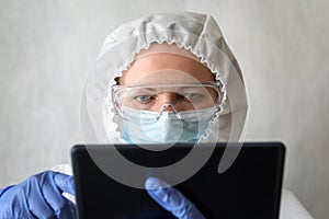 Doctor in medical PPE suit uses digital tablet