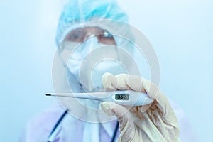 A doctor in a Medical Protective Coverall holds an electronic thermometer. The digital thermometer displays a normal temperature