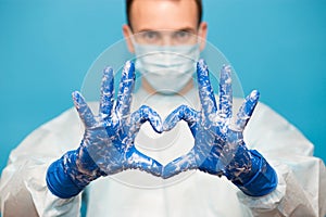 Doctor in medical suit protective mask and gloves, show heart symbol with hand in soap foam isolated on blue background. Hands