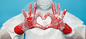 Doctor in medical suit protective mask and gloves, show heart symbol with hand in soap foam isolated on blue background. Hands