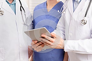 Doctor and medical team discussing patient report at tablet computer in hospital