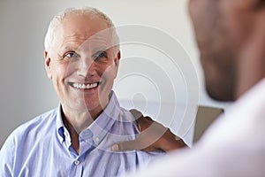 Doctor Meeting With Mature Male Patient In Exam Room photo