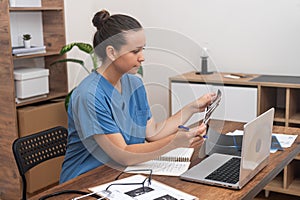 doctor meticulously examines ultrasound images, concurrently recording notes on her laptop.