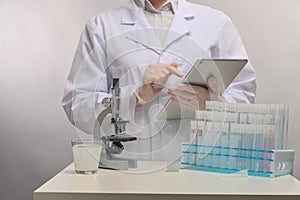 Doctor or microbiologist in protective gloves use laptop for information search on white laboratory background. Research and and