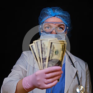 Doctor with money in hand, close-up. The nurse gives dollars on a black background. Concept of financial assistance to people