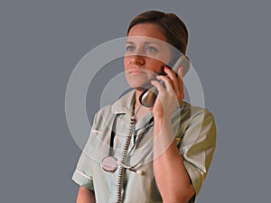 Doctor or nurse call by phone. Woman in uniform with handset and stethoscope around neck speaks