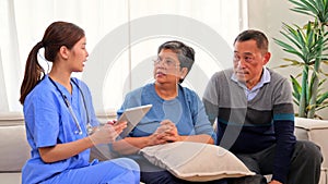 Doctor or nurse caregiver with senior patient at home or nursing home, Female doctor holding tablet visiting patient in
