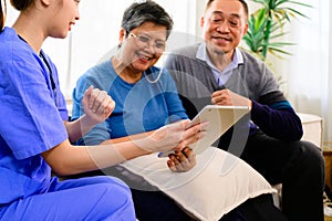 Doctor or nurse caregiver with senior patient at home or nursing home, Female doctor holding tablet visiting patient in