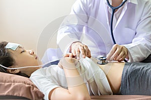 Doctor or nurse checking abdominal,listening asian child patientâ€™s belly through stethoscope,young female  physician examining