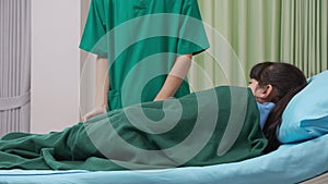 Doctor or nurse covered patient child with a blanket at hospital ward, physician care children.