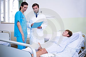 Doctor and nurse discussing over patient s leg