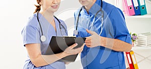 Doctor and nurse discussing something in the clinic. Two doctors in medical office close up image