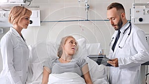 Doctor and nurse discussing with young woman patient in hospital