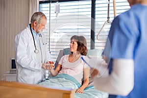 Doctor and nurse examining senior patient in bed in hospital.