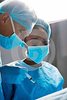 Doctor, nurse and face mask in surgery with syringe injection for medical procedure, emergency or operating room