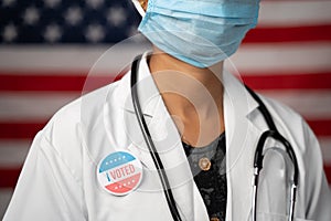 Doctor or nurse medical mask and stethoscope wearing placing I voted sticker to her apron - concept of US election with