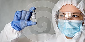 Doctor or nurse in medical PPE suit holding COVID-19 coronavirus vaccine