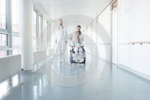 Doctor, nurse, and patient in wheelchair on hospital corridor