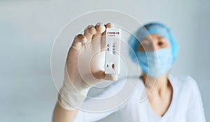 Doctor or nurse in protective face and gloves holding in hand positive COVID-19 rapid test.