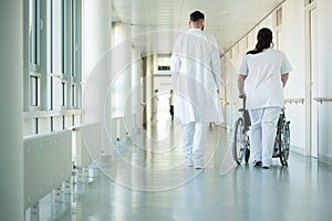 Doctor and nurse pushing wheelchair with patient in hospital photo