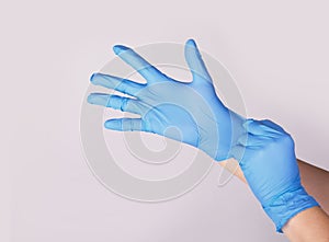 Doctor or nurse putting on blue nitrile surgical gloves, professional medical safety and hygiene photo