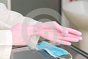 Doctor or nurse putting on pink protective gloves