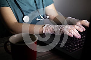 Doctor or nurse`s hands on keyboard in the dark. Long hours or overtime work of medical worker concept.