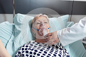 Doctor and nurse supervising senior woman breathing with oxygen mask