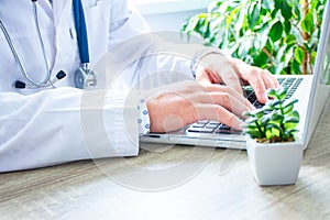 Doctor or nurse typing on laptop keyboard or computer search for necessary information online, fill patient insurance policy in w photo