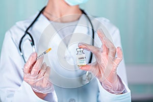 Doctor or nurse in uniform and gloves wearing face mask protective in lab holding medicine vial vaccine bottle with COVID-19