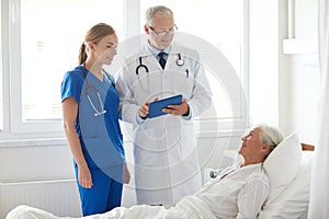 Doctor and nurse visiting senior woman at hospital