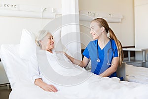 Doctor or nurse visiting senior woman at hospital