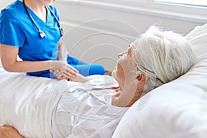 Doctor or nurse visiting senior woman at hospital