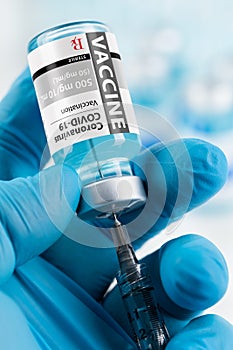 Doctor or Nurse Wearing Surgical Glove Holding Coronavirus COVID-19 Vaccine Vial and Syringe