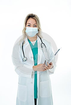 Doctor or nurse wearing white coat over green scrub and protective medical face mask
