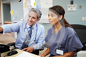 Doctor With Nurse Working At Nurses Station