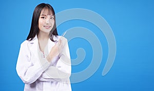 Doctor or nurse young woman wear uniform lab arms crossed holding syringe in own hands while standing over isolated blue