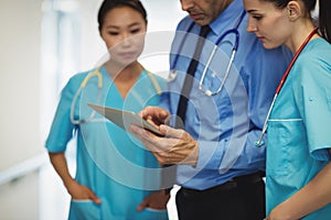 Doctor and nurses discussing over digital tablet