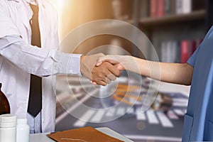 Doctor and Nursing assistant patient meeting at the hospital and shaking hands, healthcare and medicine banner.