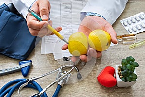 Doctor nutritionist during consultation held in his hand and shows patient yellow apple. Counseling and explanation of use of appl