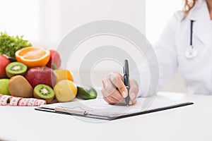 Doctor nutritionist writing on paperwork in office